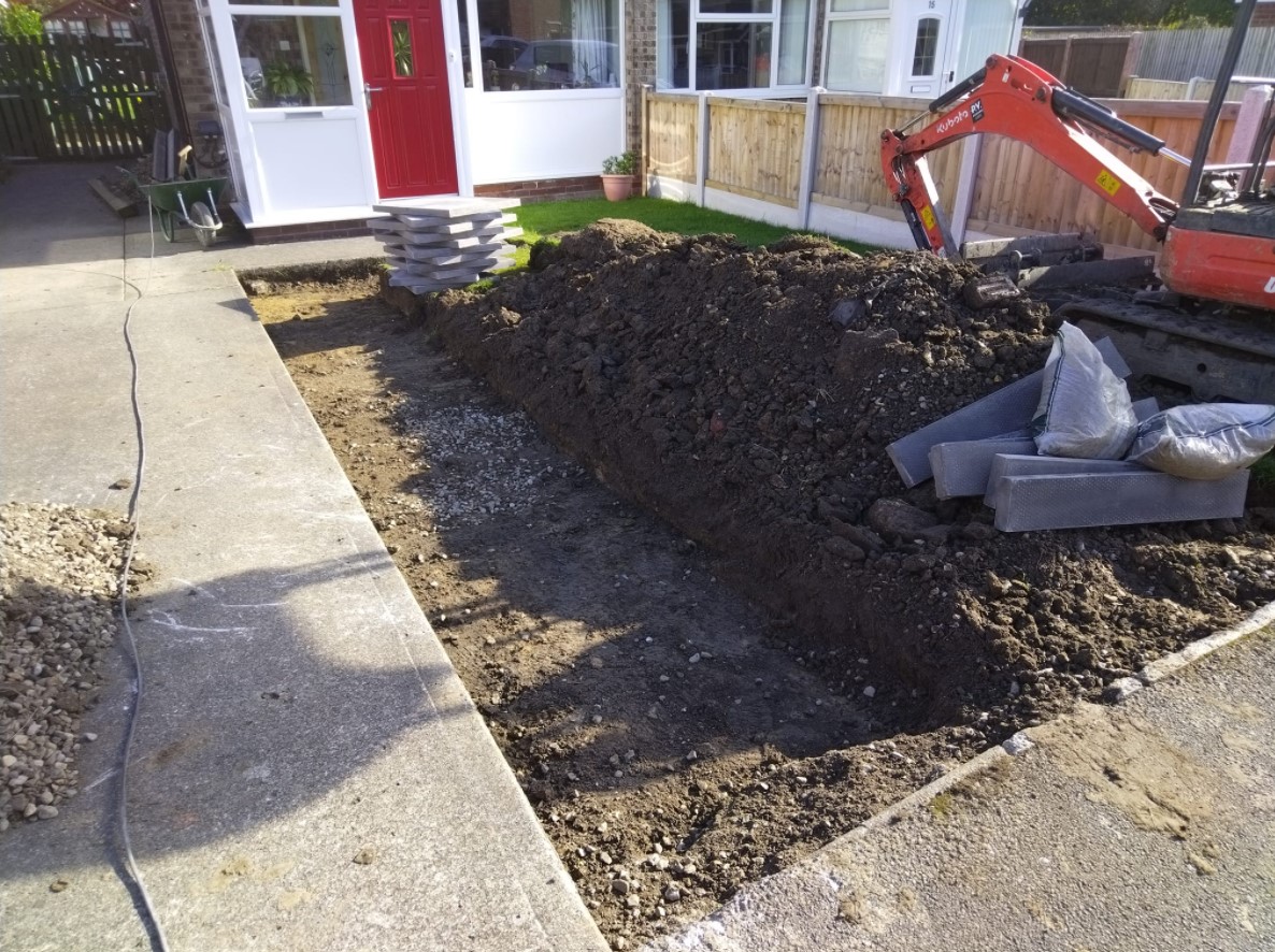 Excavation in progress with a small digger and prepared paving materials